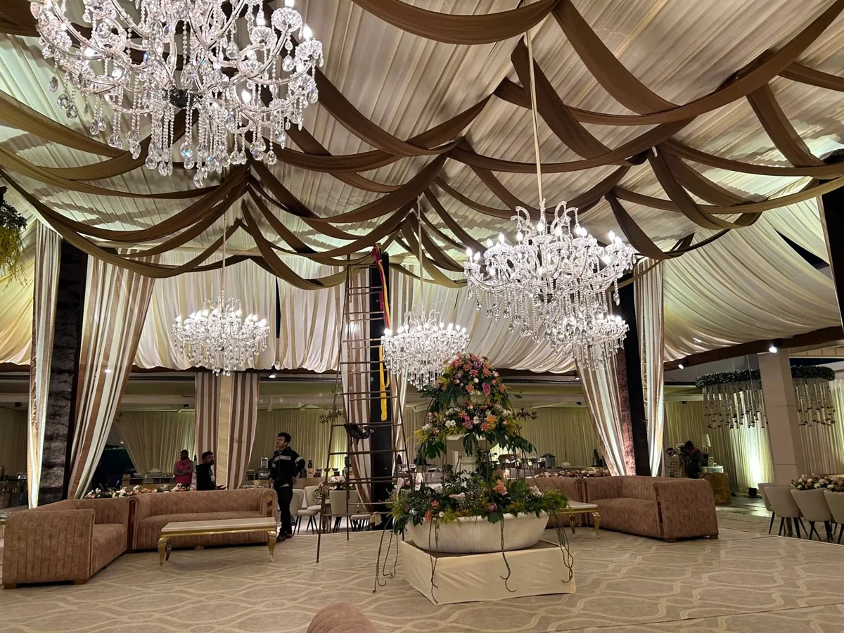 Cream and bronze ceiling drapes with crystal chandeliers over a reception lounge