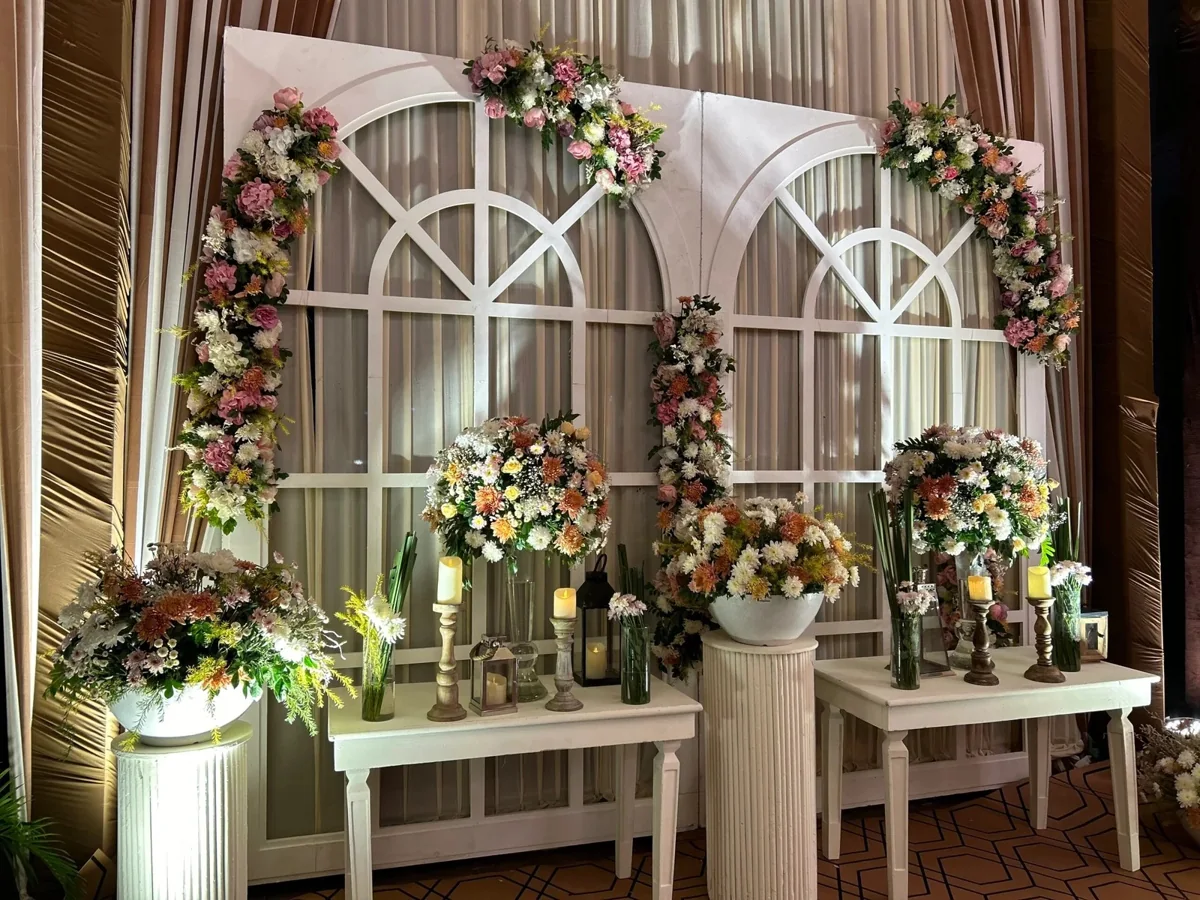 White architectural arches with pink and white flowers, candles and plinths