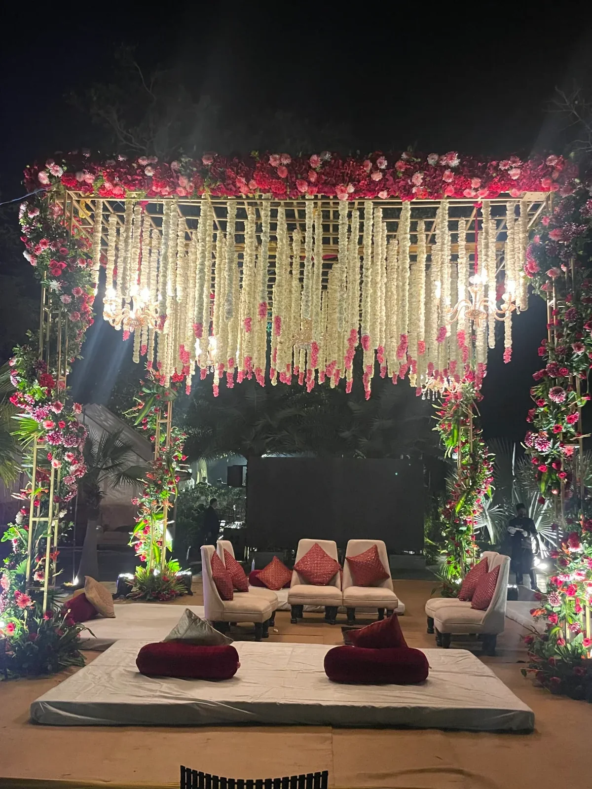 Pink floral pavilion with cascading white garlands and chandeliers at night