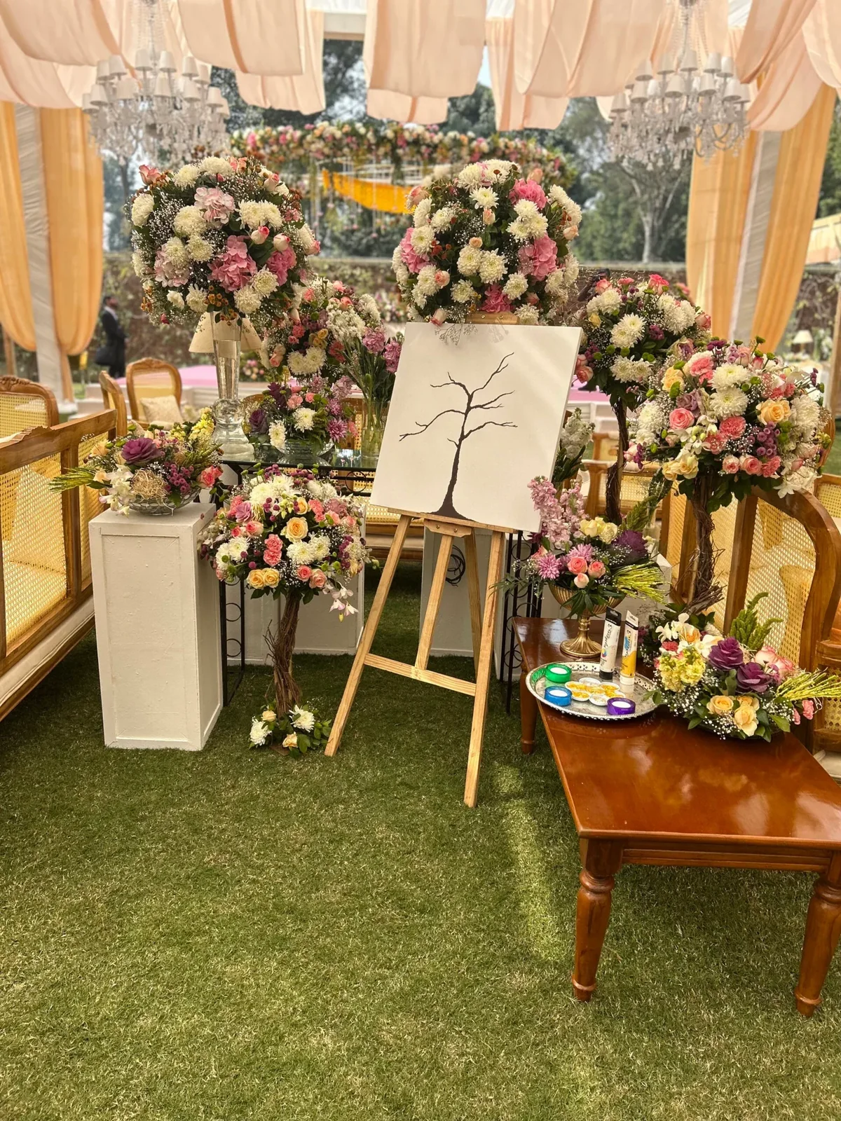 Pastel flower arrangements around an easel beneath peach garden drapery