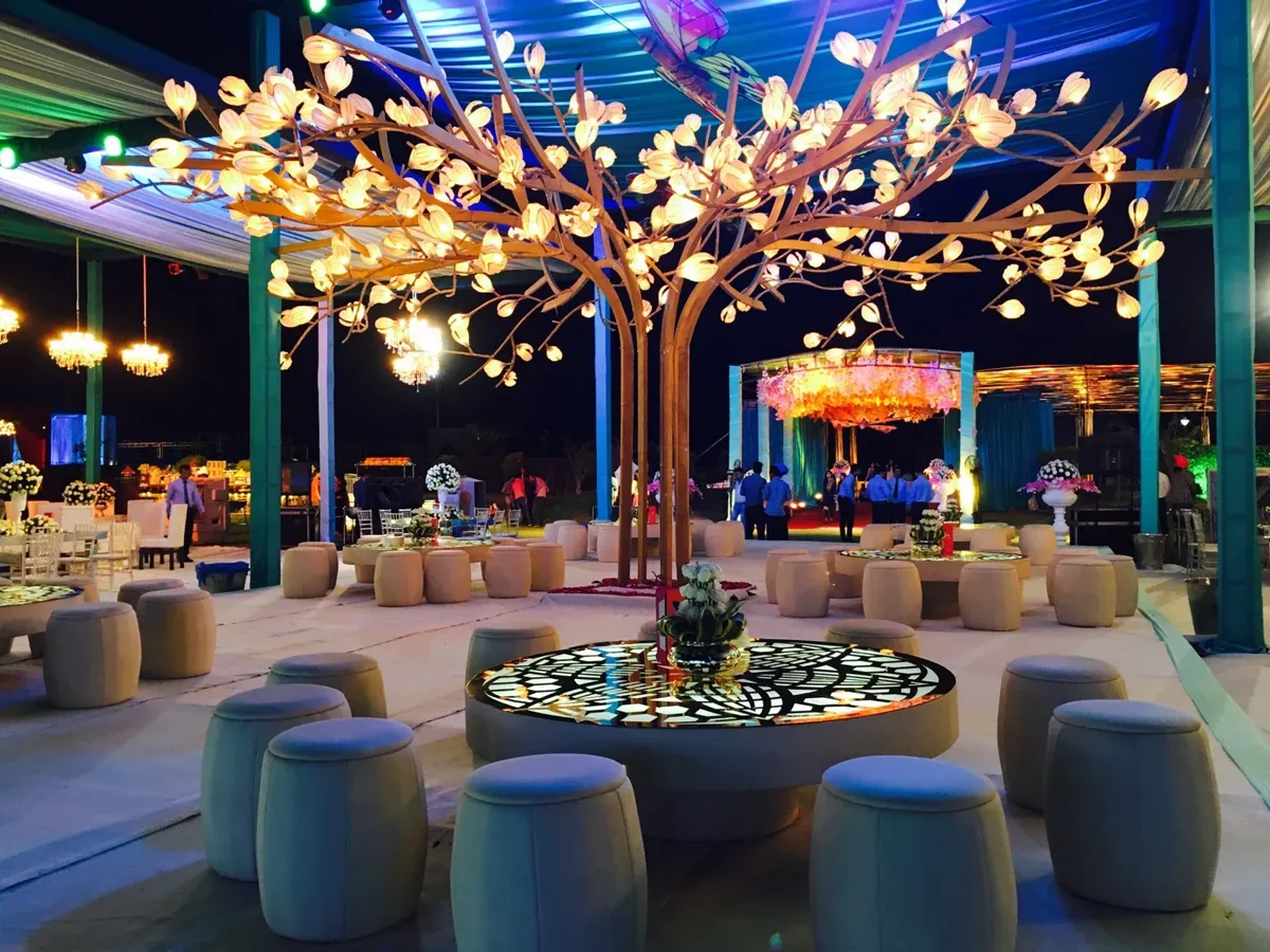 Glowing sculptural tree above circular lounge tables in a blue-lit venue