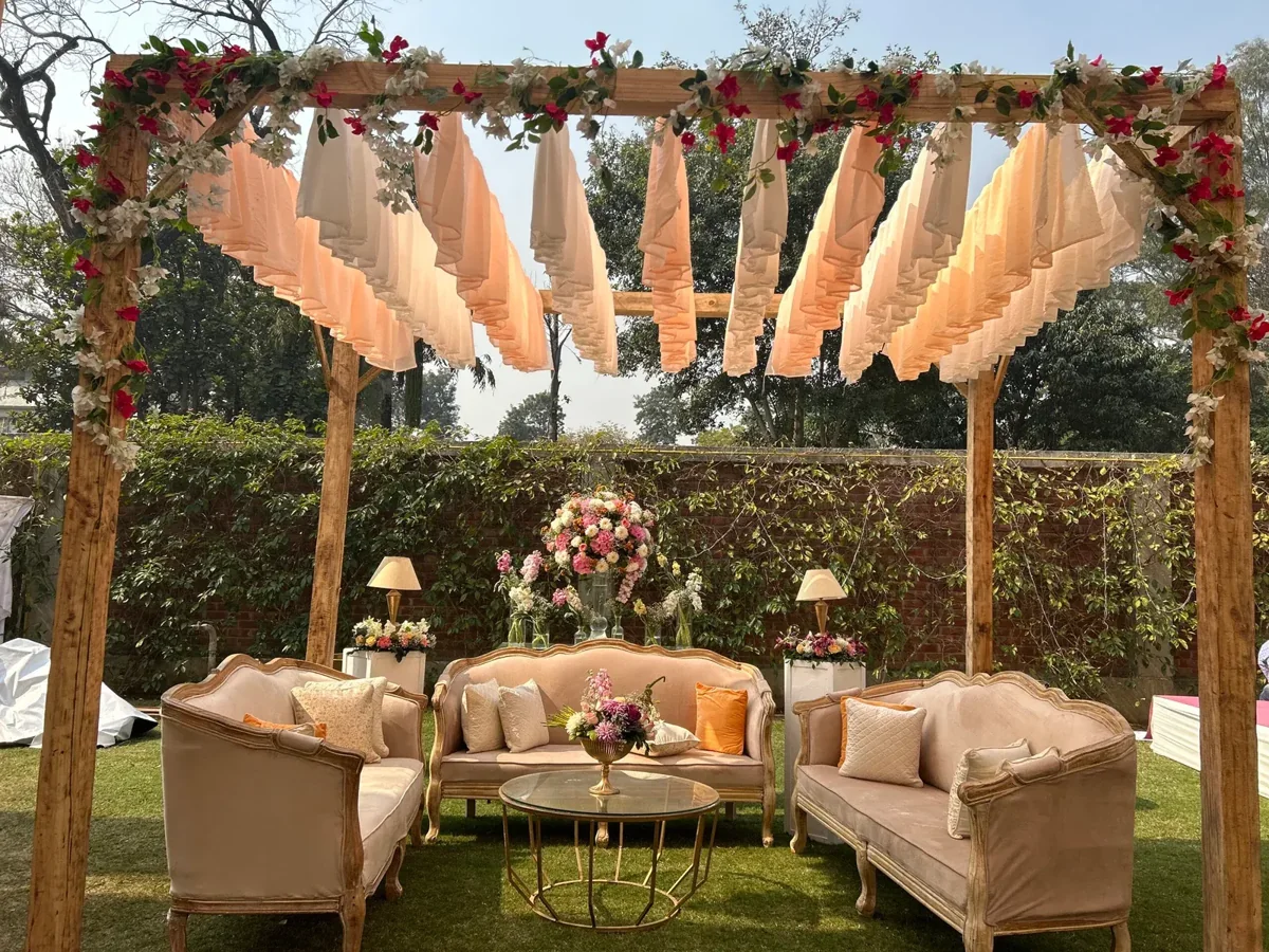 Vintage cream sofas under peach fabric and a flower-wrapped timber canopy
