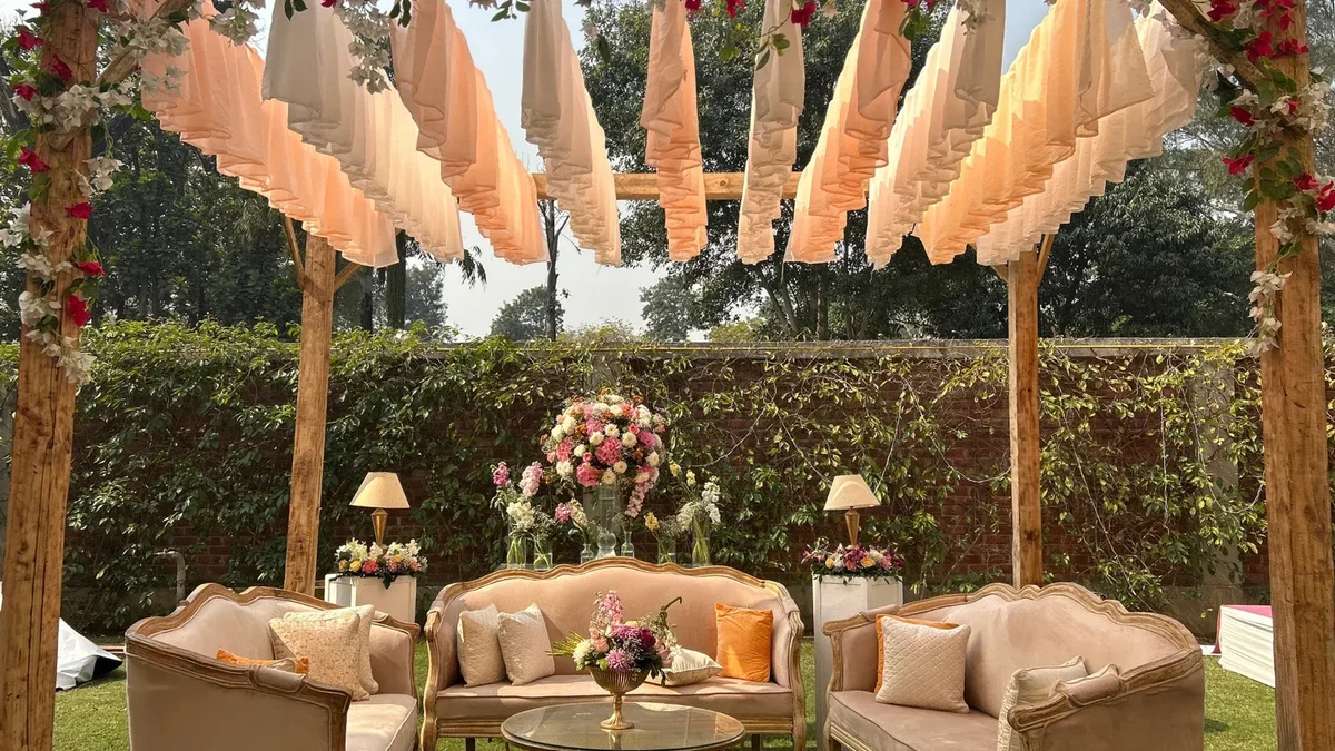 Peach garden canopy framing a cream lounge and floral table