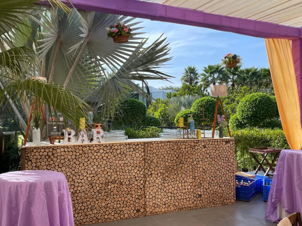Rustic timber bar surrounded by palms and lavender and yellow drapes