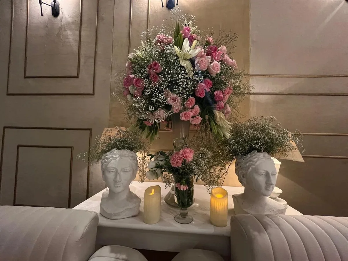 Pink flowers, sculptural white vases and candles in a decorative display