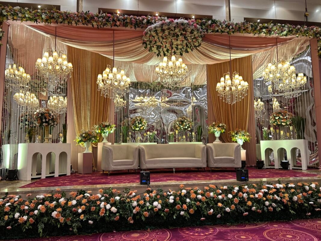Floral reception stage beneath statement chandeliers