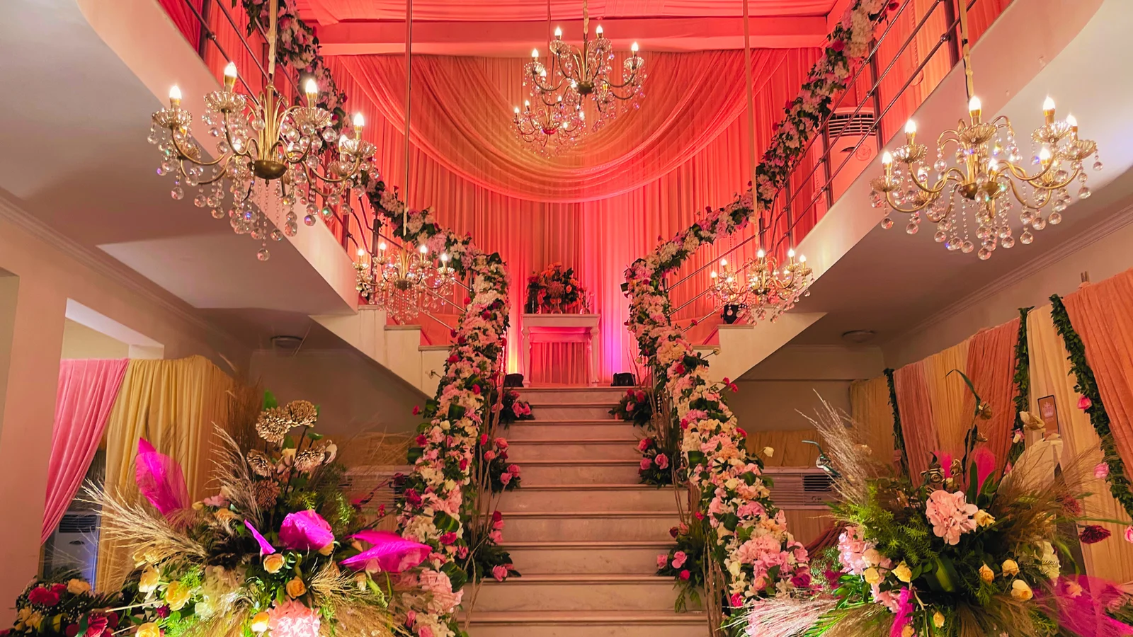 Flower-lined staircase beneath glowing chandeliers